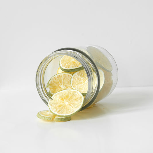 Glass jar with sliced freeze dried limes on a white background