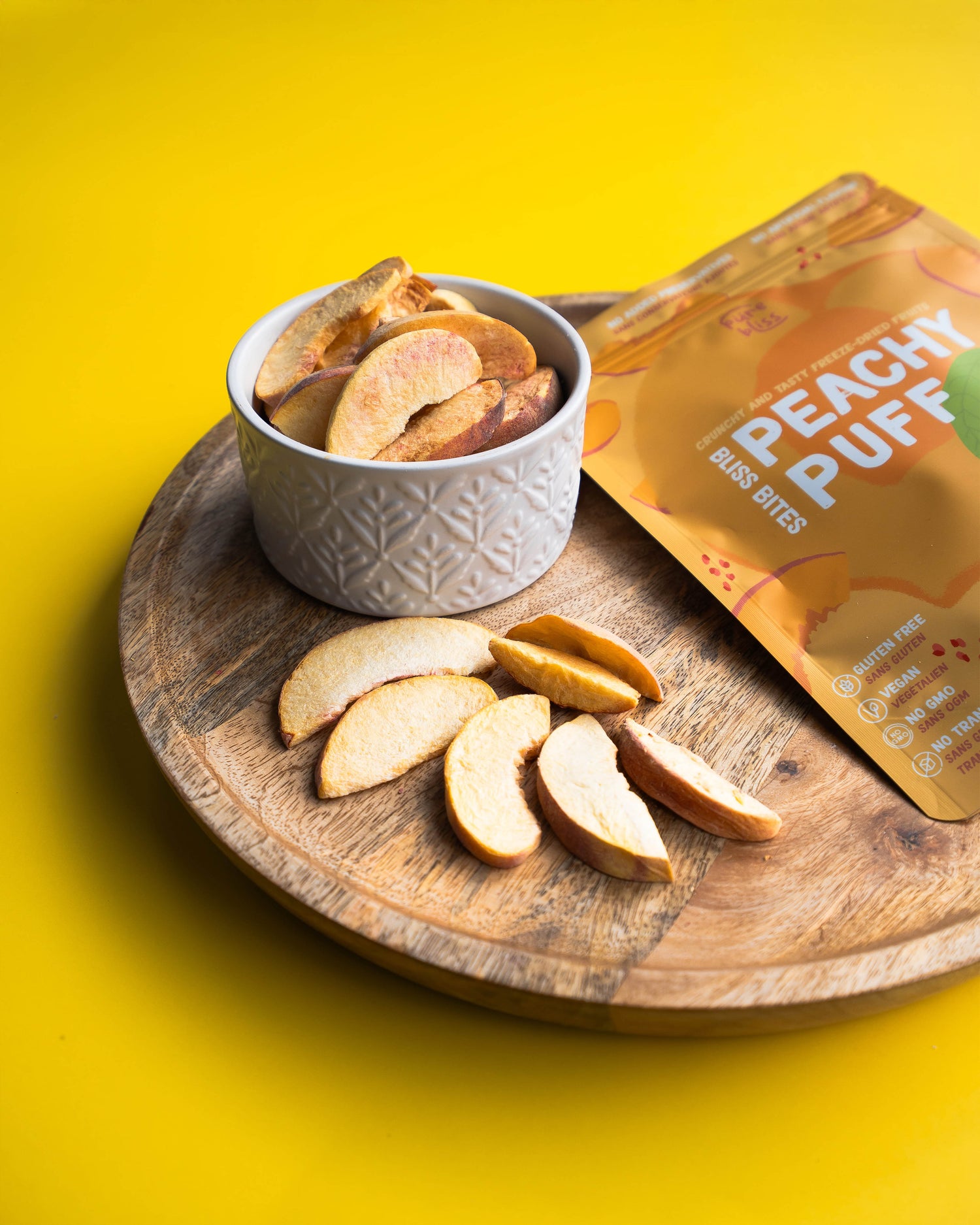 Peach bites in a bowl with a 'Peachy Puff' package on a yellow background