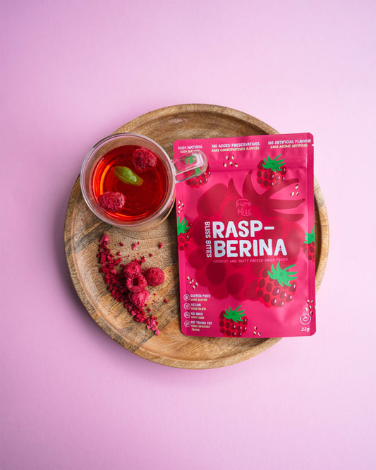 Rasp-Berina package with raspberry tea on a wooden tray against a pink background
