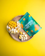 Tropical Fruit Fest snack package with a bowl of freeze dried fruits (banana, mango, and pineapple) on a yellow background
