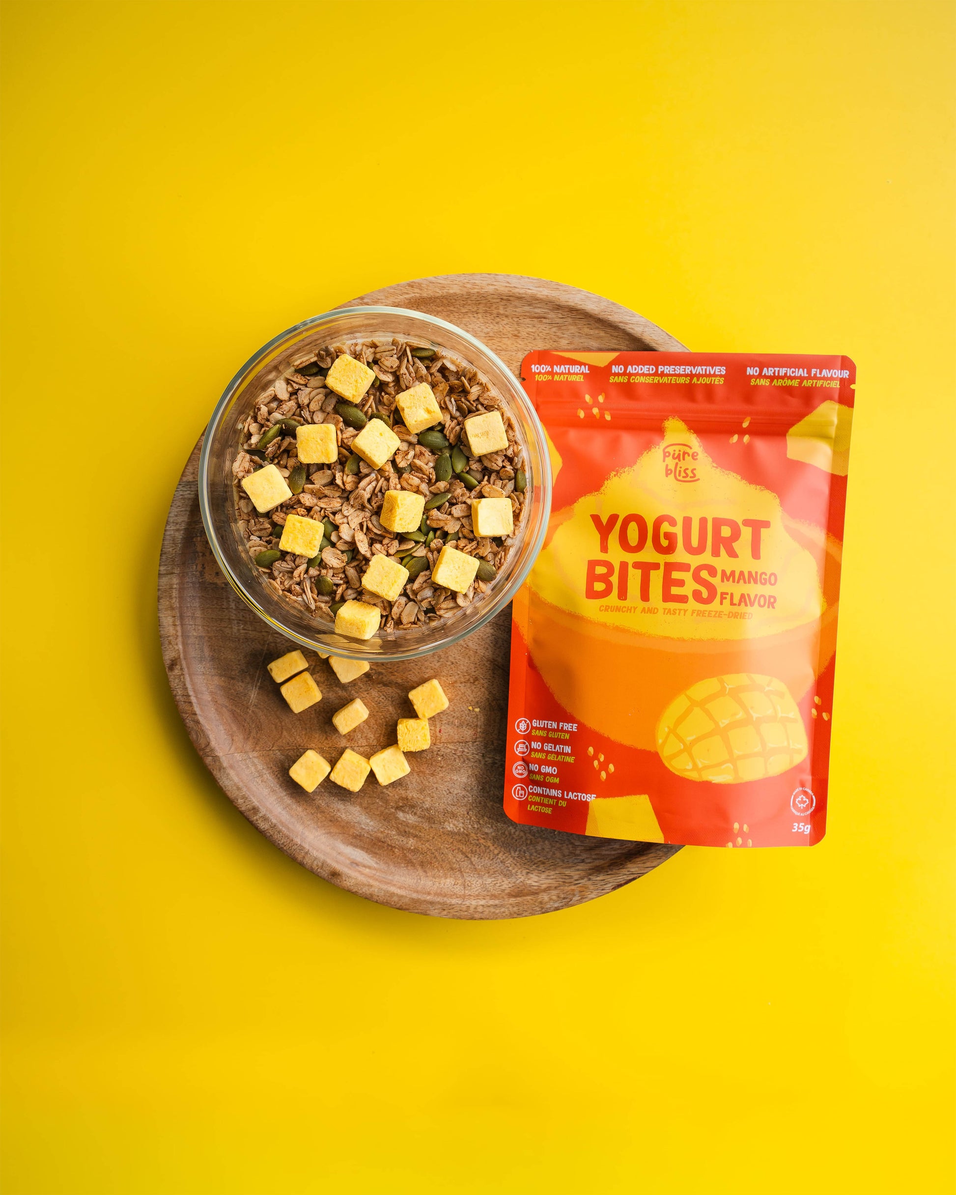 Yogurt bites package with a glass of yogurt and granola on a yellow background