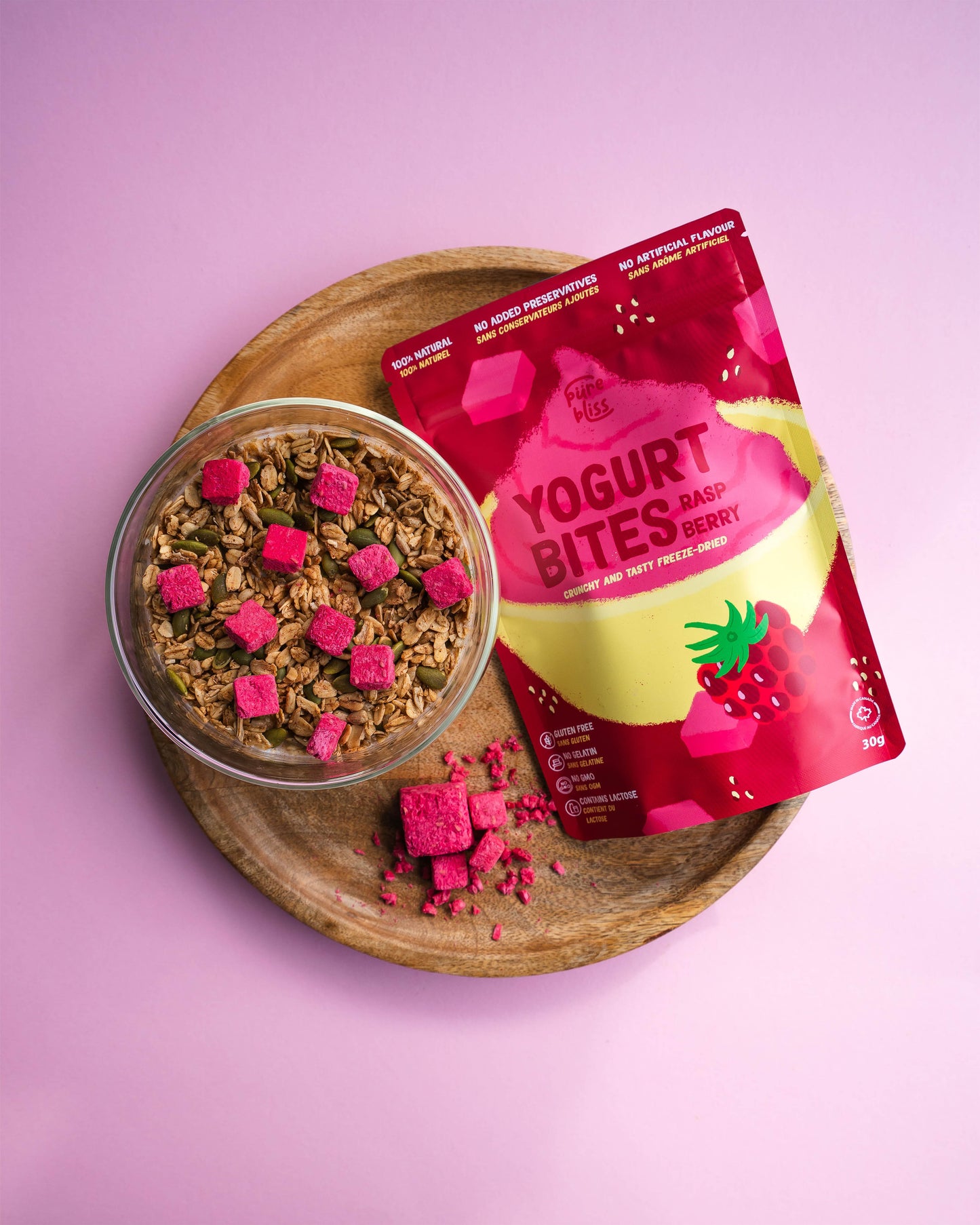 Yogurt bites package with a bowl of granola on a pink background