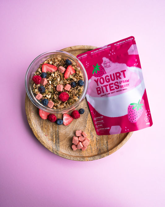 Yogurt bites package with a bowl of granola and berries on a pink background